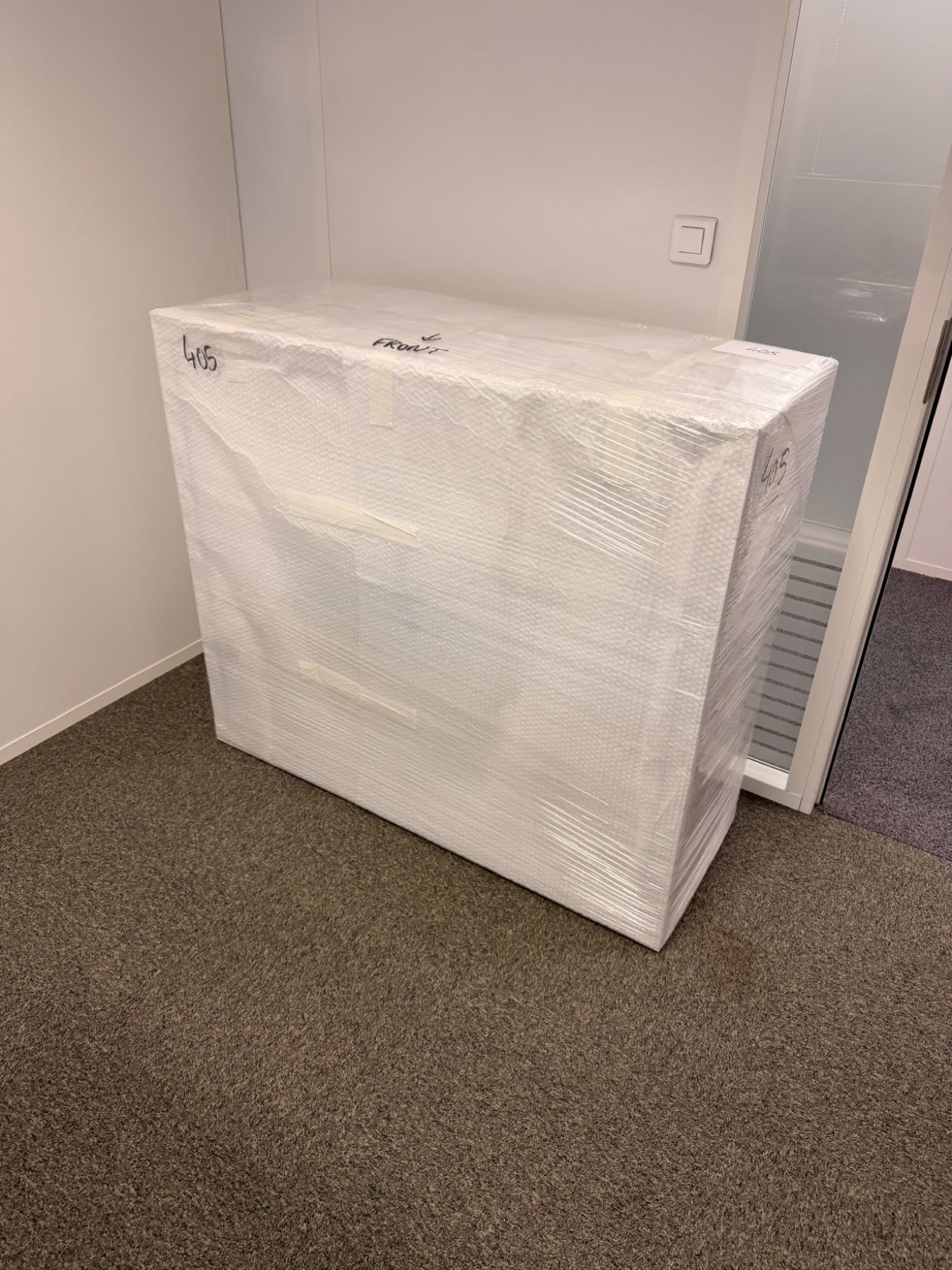 Commode emballée en film blanc et numérotée dans un couloir de bureaux