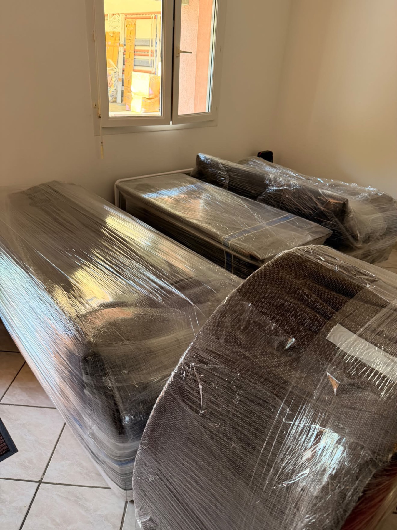 Matelas et sommier emballés sous film étirable dans une chambre