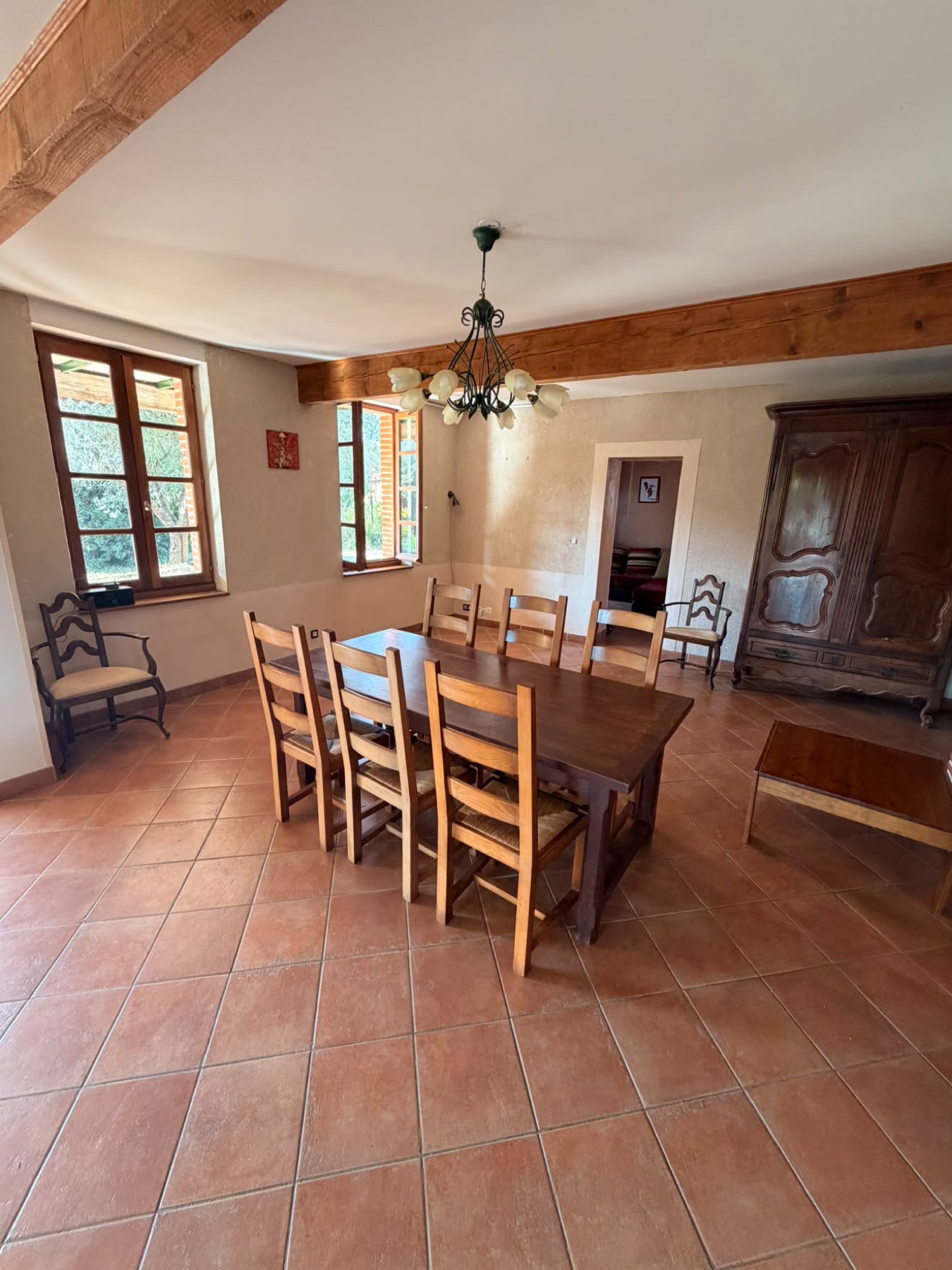 Salle à manger d'une maison à poutres avec table et armoire anciennes